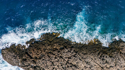 Zakynthos Greece coastline aerial top view with rugged rock headland waves hitting cliffs and surrounding deep blue Ionian Sea landscape