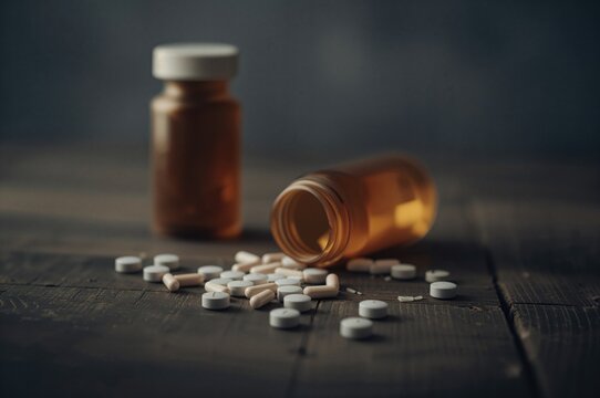 Concept of substance abuse, dependency, and self-harm - medication bottle and tablets on surface