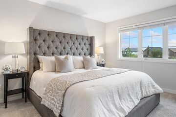 Large bed with a white comforter and pillows, and a gray headboard