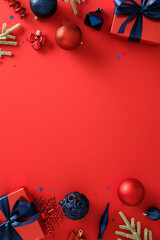 Christmas composition with red gifts, blue ribbons, ornaments and fir branches on red background,...