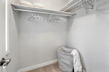 Small closet with a white wall and a gray basket