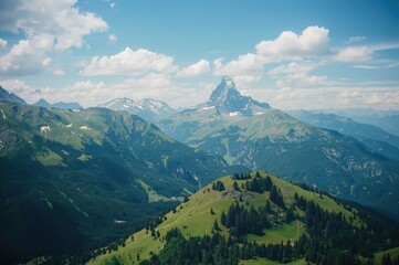 Fototapeta premium Wide-angle shot of three majestic peaks with lush green mountains, clear sky, and forest in summer