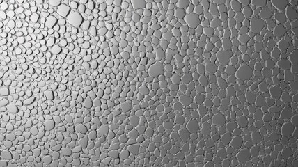 Close-up of water droplets on a textured surface, creating an abstract pattern in shades of gray.