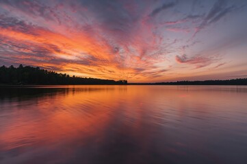 Obraz premium A breathtaking sunset illuminating tranquil lake surfaces with warm orange tones.