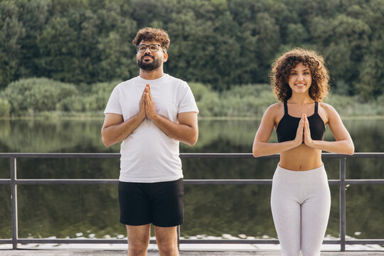 Arab couple practicing yoga in prayer position by the lake
