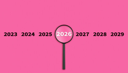 Lens, magnifying glass focusing on the year 2026 on a Pink background. Financial or stock market strategies and past and future events.