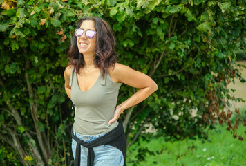 Fototapeta premium Smiling woman portrayed in the countryside in front of a large tree. The woman is a beautiful thirty-eight year old brunette of Caucasian origin