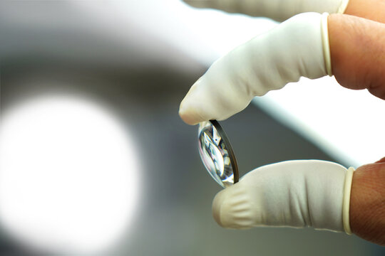 In lens production, an expert employee checks the camera lens.
