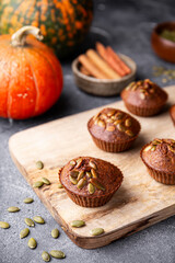 Autumn pumpkin cupcakes or baked muffins with fresh pumpkin and pumpkin seeds for Thanksgiving day vertical photo