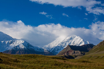 Fototapeta premium Snow-covered mountains around Lenin Peak or Ibn Sina Avicenna Peak, high-altitude landscape, Pamir range, rugged terrain, glacier view, cold climate, mountain scenery, alpine environment