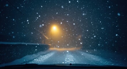 driving on snow-covered road during heavy blizzard at night. view from car's windshield as street lamp illuminates falling snowflakes. winter travel.