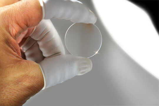 In lens production, an expert employee checks the camera lens.