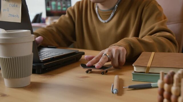 Close up of unrecognizable programmer playing with fingerboard while working on laptop in office