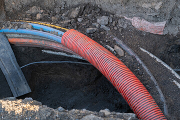 Various electrical wires are buried beneath a street walkway. Cobblestones are removed to allow underground cable installation