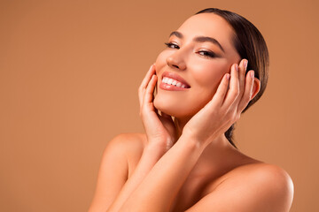 Beautiful young woman with flawless skin touching her face on beige background, embodying elegance