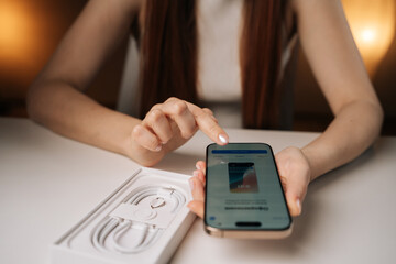 Ufa, Russia - 17 August 2025. Woman unpacking new iPhone 16 pro, examining sleek device and...