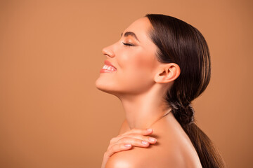 Beautiful young woman posing on warm beige background showcasing flawless skin and natural beauty