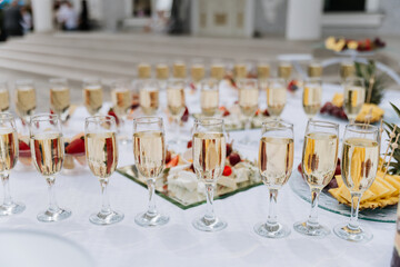 Elegant outdoor wedding catering setup with champagne glasses and fruit platters