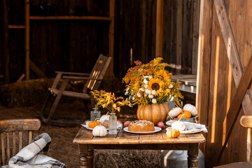 Centrepiece floral composition with natural sunflowers in a pumpkin vase. Beautiful fall seasonal wedding decor or thanksgiving family dinner arrangement outdoors. Countryside style, cottage core