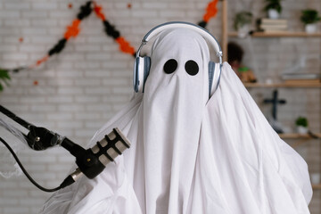 Funny ghost in a white sheet recording a podcast or blog