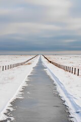 Frozen rural road leading to horizon, winter minimalism landscape with snow and cloudy sky
