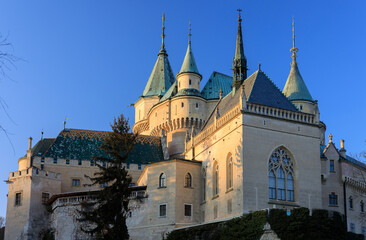 A close-up of the beautiful Bojnice Castle during sunset, with its majestic walls and turrets