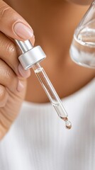 A close view of exfoliating serum being applied with a glass dropper, its glossy finish enhancing the skin against a refined, science-driven abstract background.
