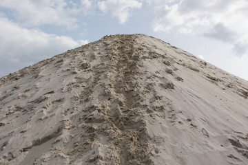 Sandy hill with trail under cloudy sky
