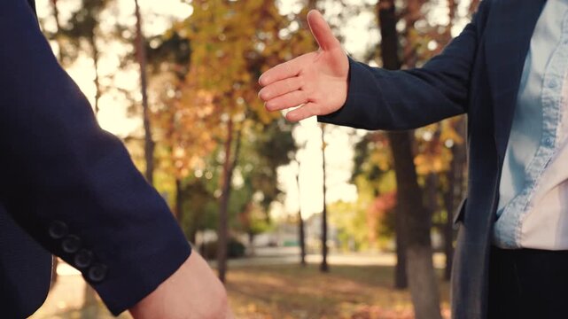 Business meeting. Businesswoman shakes hands with her partner on street. Businesspeople shake hands. Successful contractual cooperation. Businessmen in suits greet each other with gestures on street