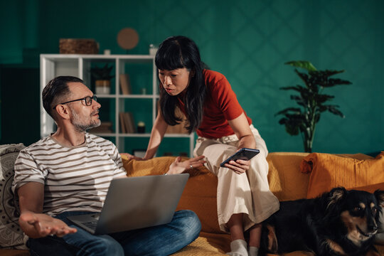 Couple arguing about finances on laptop and smartphone at home