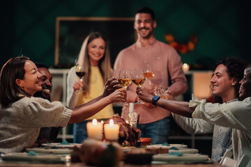 Happy friends toasting with white wine at thanksgiving dinner