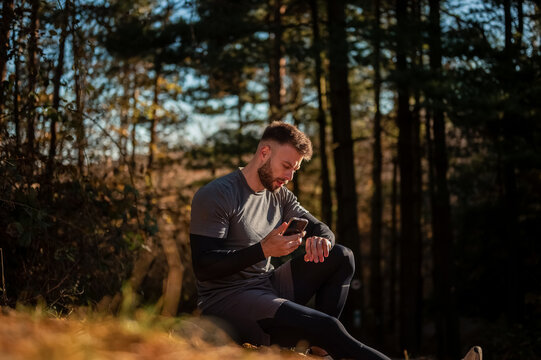 Athlete checking smartwatch during training break in forest