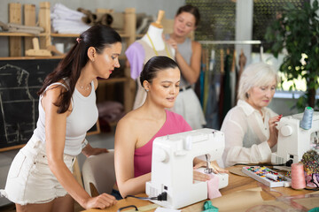 Group of women of different ages sew and work with mannequin during sewing master class