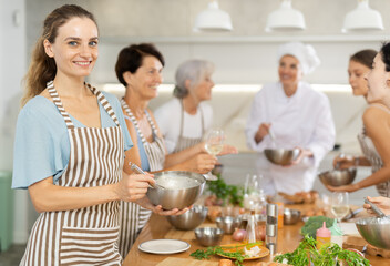 Girl while studying at culinary workshop school, cooks appetizing sauce, marinade, dough in bowl.