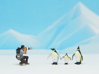 Mini toy of action figure at outdoor with blurred background. Miniature photography concept design. Minifigure wildlife photographer character with penguins at antarctica. © awstoys