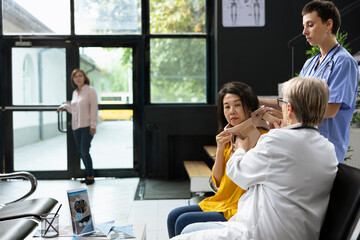 Doctor placing cervical neck brace on injured patient during medical checkup, assisted by nurse to...