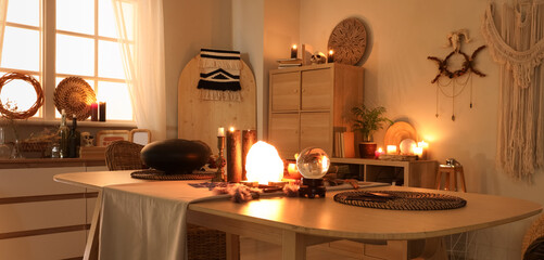 Interior of witch's room with magic attributes, table and burning candles in evening