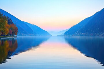 Obraz premium Calm lake reflecting autumnal mountains at dawn