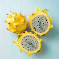 Two vibrant yellow dragon fruits on a pale blue background, showcasing their unique spiky exterior and white, speckled flesh.