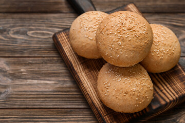 Board of fresh buns with sesame seeds on wooden background