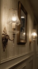 Elegant wall sconces with crystal glass shades illuminate a hallway with decorative wallpaper and molding.