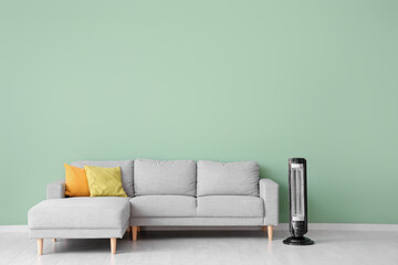Interior of stylish living room with modern electric heater and grey sofa