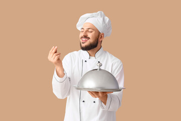 Male chef with cloche on beige background