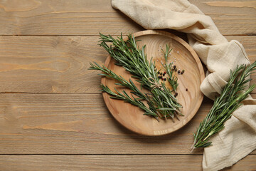 Plate with fresh rosemary twigs, salt and peppercorns on wooden background