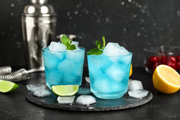 Glasses of tasty Blue Lagoon cocktail with mint and lime on black background