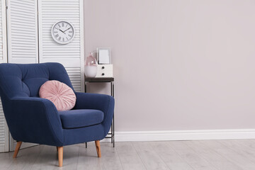 Comfortable armchair and decor near beige wall. Space for text