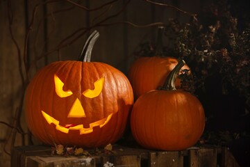 Scary jack o'lantern pumpkin on wooden bench in darkness. Halloween decor
