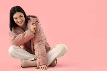 Young woman in stylish puffer jacket on pink background