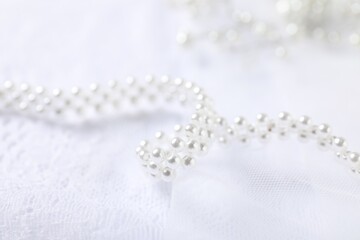 Beautiful pearl necklace on lace fabric, closeup
