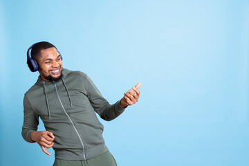 African american upbeat man pretending to play air guitar and listening to music on his headset,...